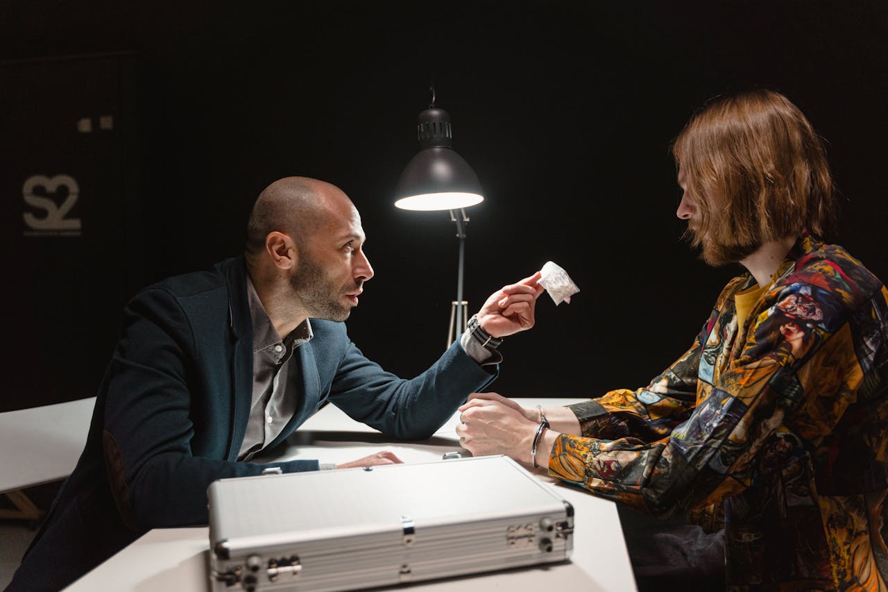 Crafting Captivating Headlines: Your awesome post title goes here Two adults in a dimly lit room negotiating over a small package at a table.